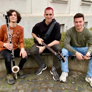 Zu sehen sind drei junge Musiker mit ihren Instrumenten.
