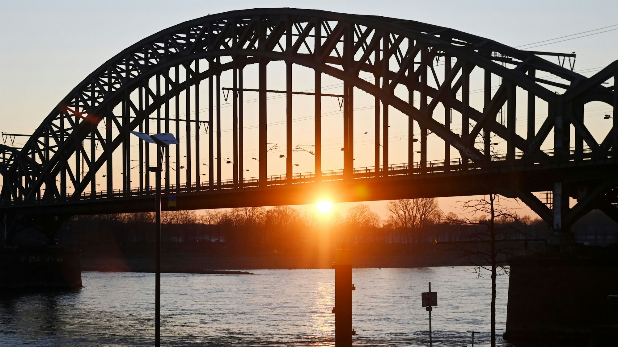 Die Sonne geht am frühen Morgen hinter der Südbrücke am Kölner Rheinufer auf. Deutschland erwartet am Wochenende das heißeste Aprilwochenende seit Beginn der Wetteraufzeichnungen. (Symbolbild)