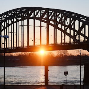 Die Sonne geht am frühen Morgen hinter der Südbrücke am Kölner Rheinufer auf. Deutschland erwartet am Wochenende das heißeste Aprilwochenende seit Beginn der Wetteraufzeichnungen. (Symbolbild)