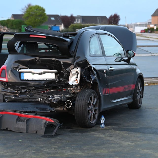Ein am Heck stark beschädigtes Auto steht auf einer flachen Fläche.