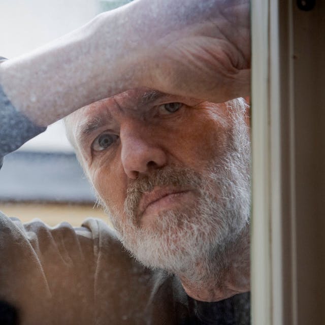 Der niederländische Fotograf Anton Corbijin blickt durch eine Fensterscheibe.