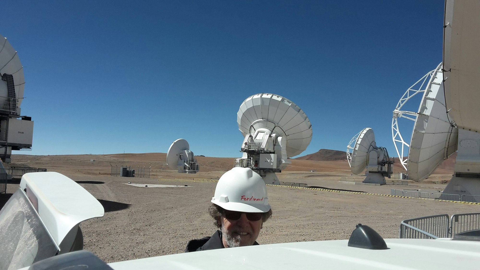 Ferdi Patt auf der Hochebene Chajnantorin in Chile auf 5000 Meter. Im Hintergrund einige der ALMA-Antennen.