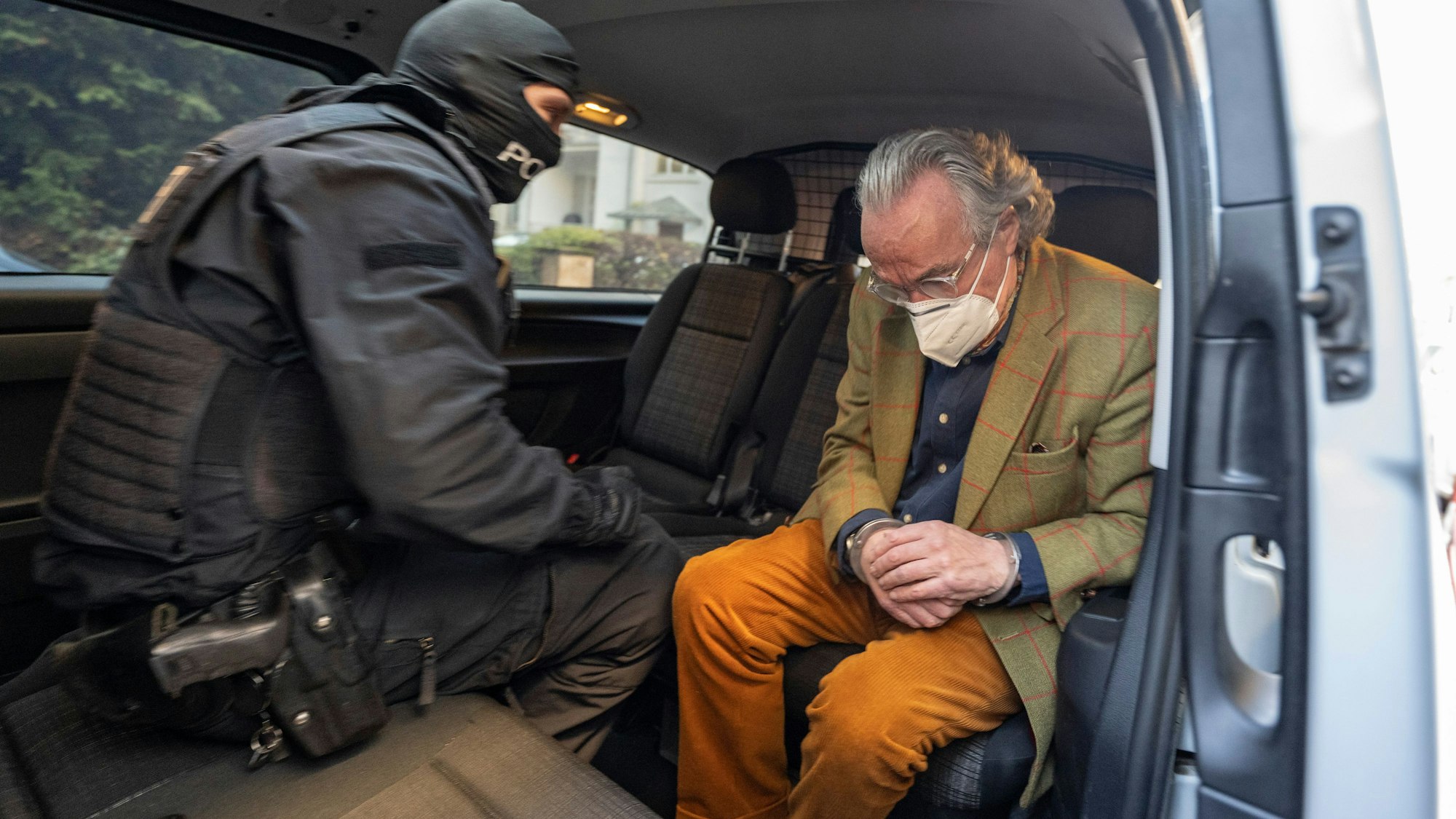 Bei einer Razzia gegen sogenannte „Reichsbürger“ sitzt ein vermummter Polizist, nach der Durchsuchung eines Hauses, mit dem festgenommenen Heinrich XIII Prinz Reuß (r) in einem Polizeifahrzeug.