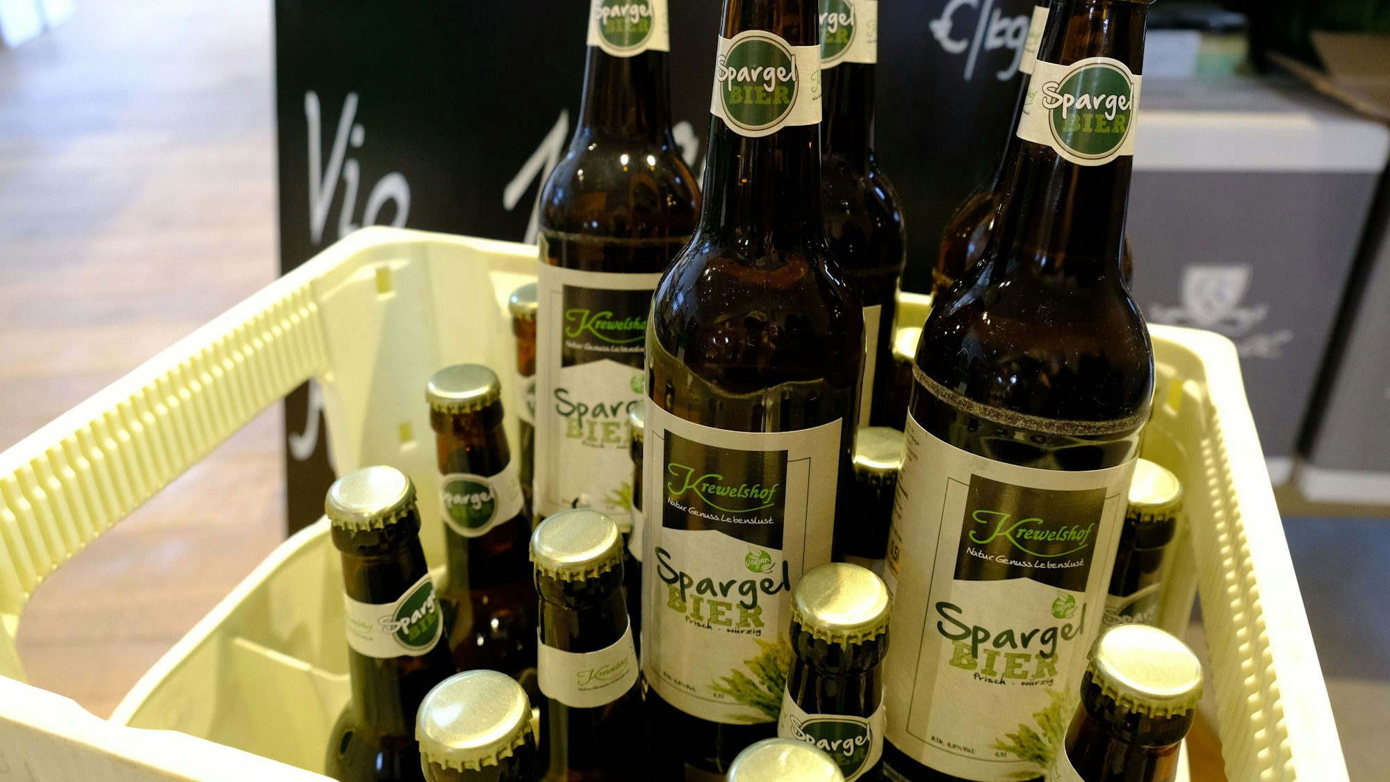 Mehrere Bierflaschen mit dem Aufdruck „Spargelbier“ stehen auf einer Bierkiste.