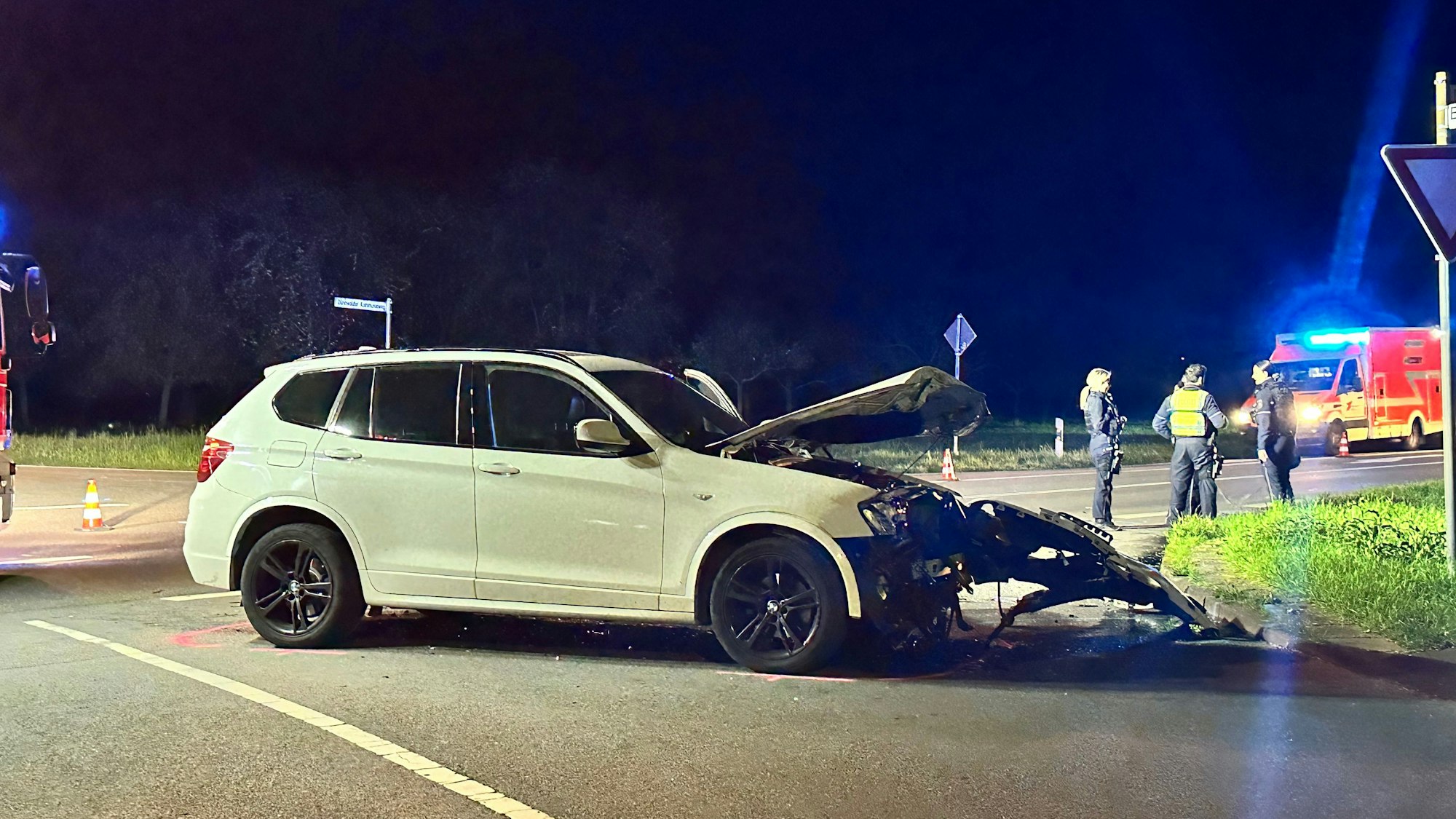 Ein beschädigter weißer BMW steht an einer Kreuzung.