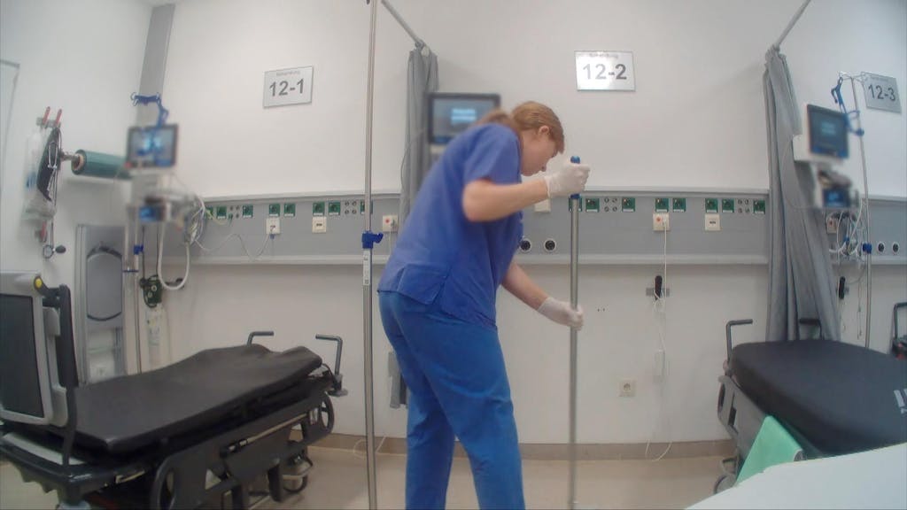 Eine Frau im blauen Kittel putzt einen Behandlungsraum im Krankenhaus. Sie ist Reporterin für Team Wallraff bei RTL.