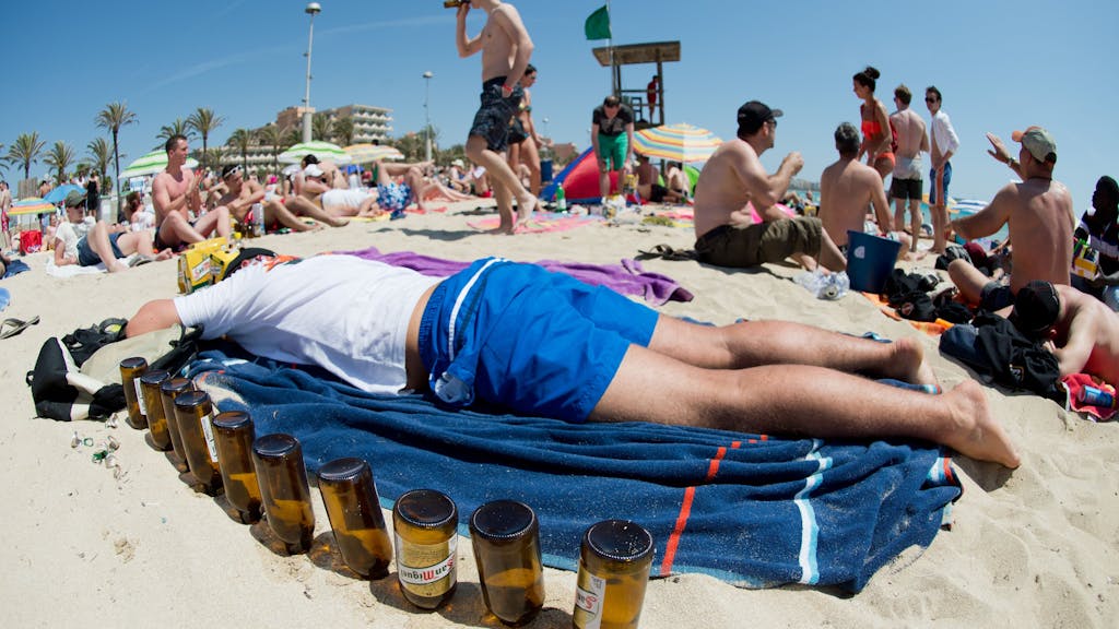 Ein deutscher Tourist liegt am 06.06.2013 schlafend auf einer Luftmatratze neben leeren Bierflaschen am Strand von Arenal auf der Mittelmeerinsel Mallorca.