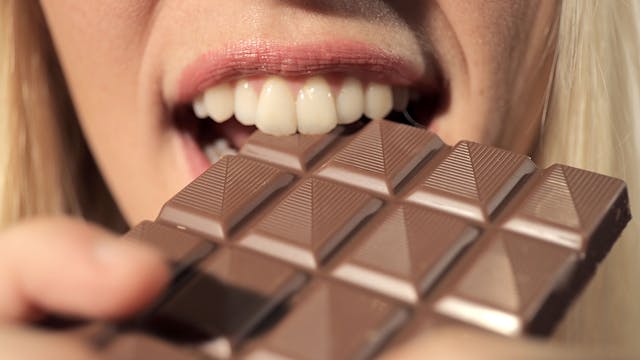 Eine Frau beißt in eine Tafel Schokolade.