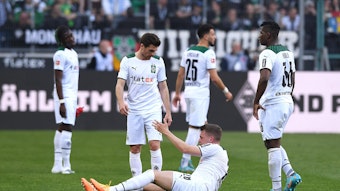 Spieler von Borussia Mönchengladbach hilft seinem Team-Kollegen auf.