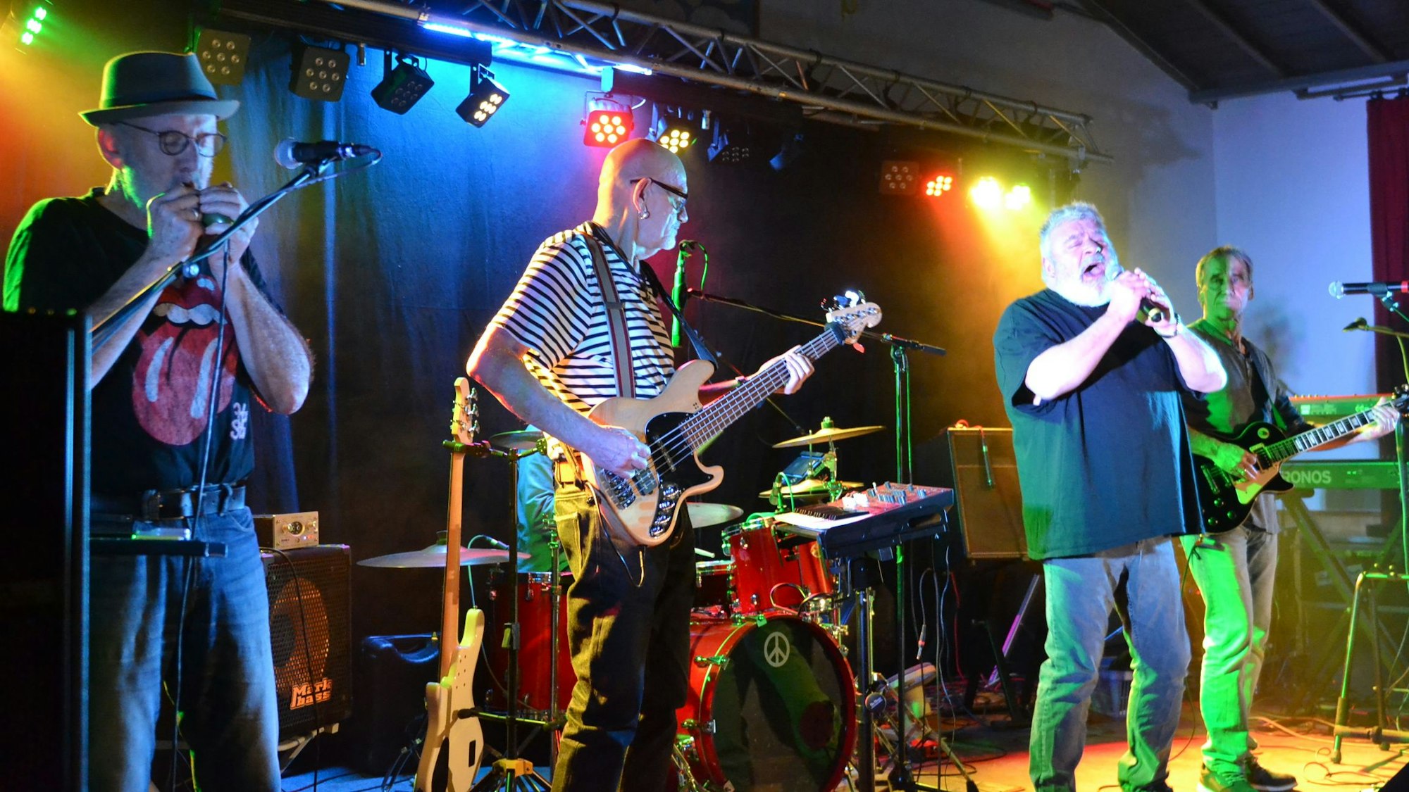 Musiker der Band "Rostfrei" stehen auf der Bühne, spielen E-Gitarre und singen.