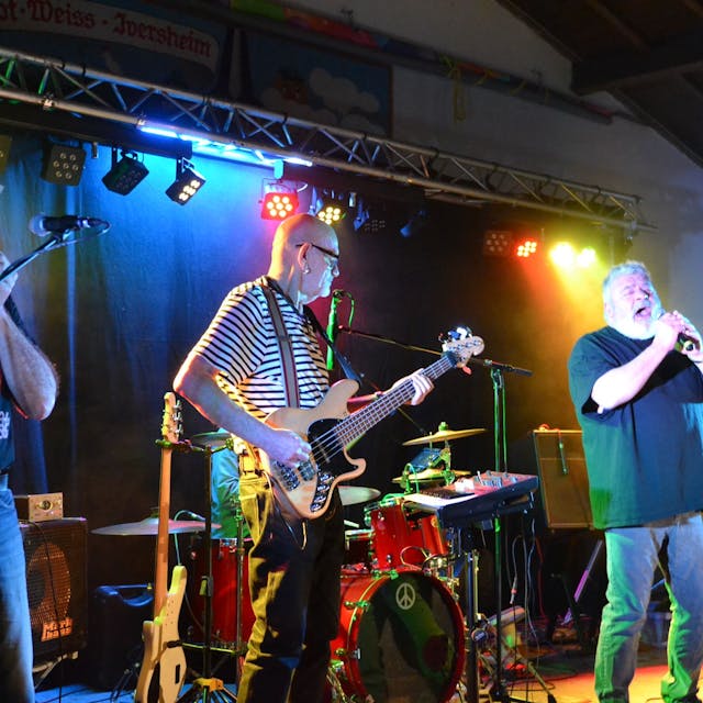 Musiker der Band "Rostfrei" stehen auf der Bühne, spielen E-Gitarre und singen.