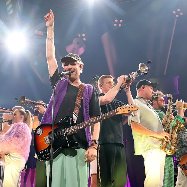 Mehrere Mitglieder der Brasspop-Band Querbeat stehen auf der Bühne der Kölner Lanxess Arena.