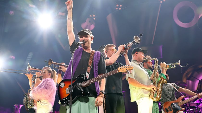 Mehrere Mitglieder der Brasspop-Band Querbeat stehen auf der Bühne der Kölner Lanxess Arena.