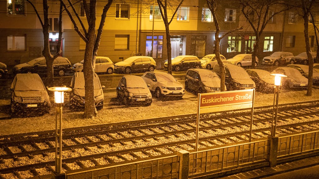 Foto von oben zeigt schneebedeckte Autos an einer KVB-Haltestelle in Köln.