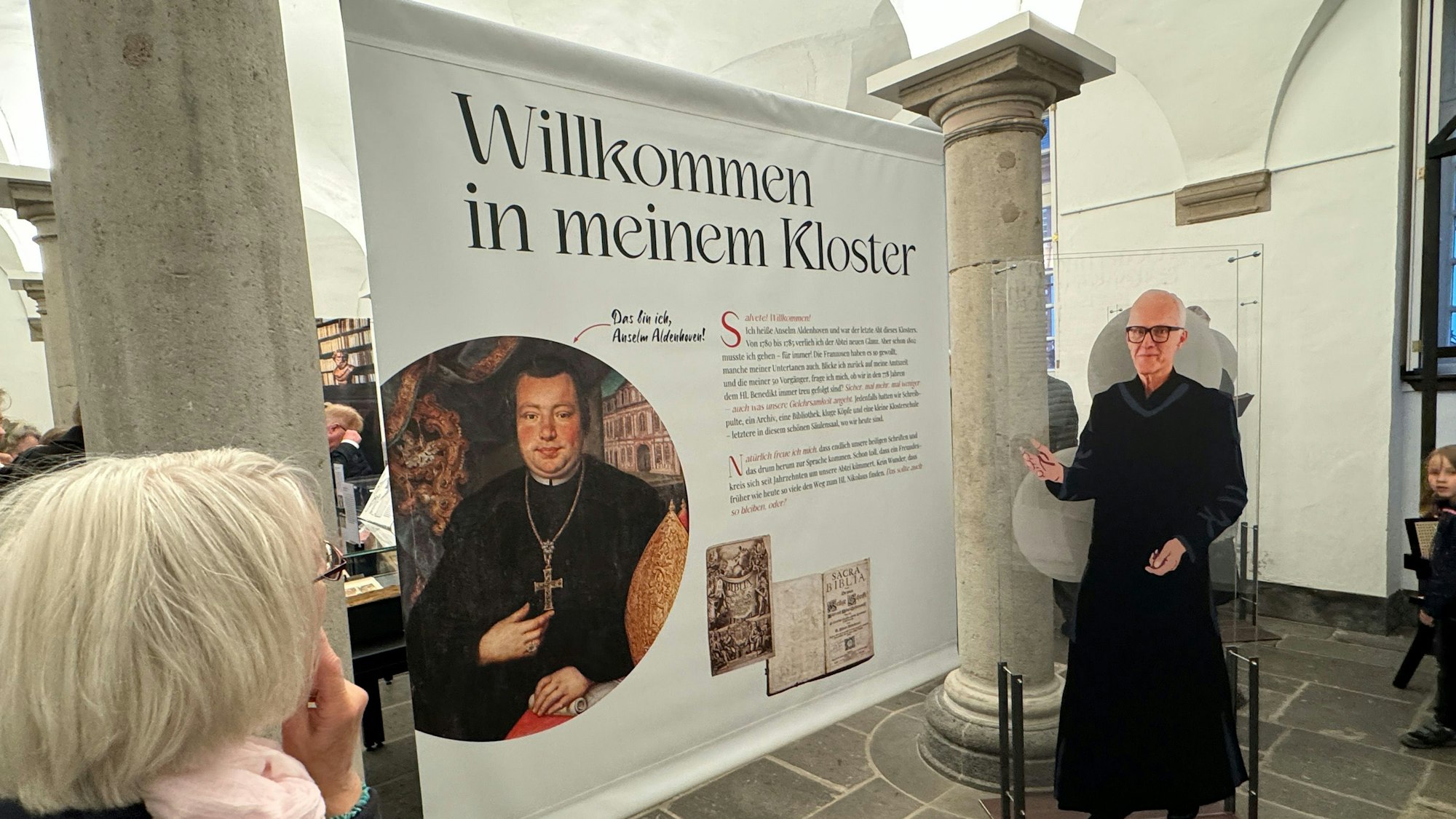 Zu sehen ist eine große Schautafel neben der eine Pappfigur Jürgen Rüttgers in Mönchsgewand zeigt.