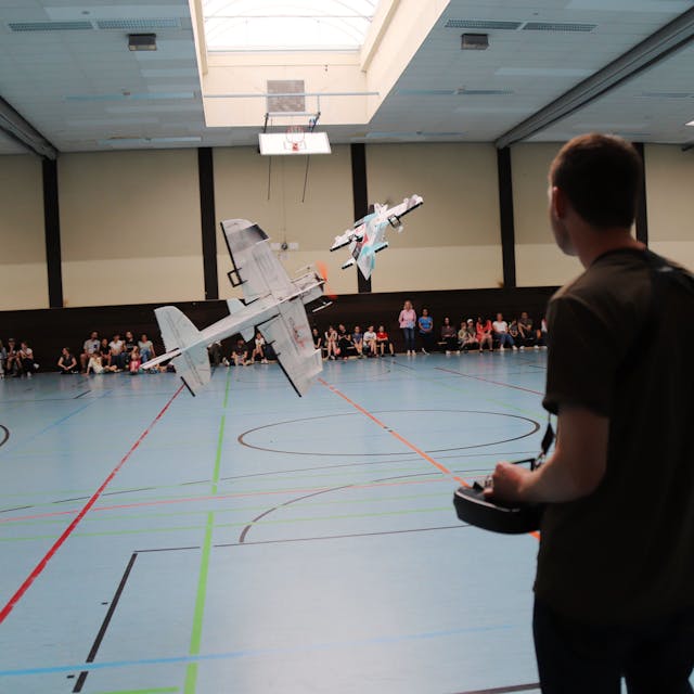 Ein junger Mann steuert ein Modellflugzeug in der Sporthalle im Schulzentrum Niederkassel.