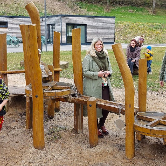 Bürgermeisterin Jennifer Meuren, Annegret Dreimüller und Guido Waters stehen am Kleinkinderspielplatz. Einige Kinder spielen.