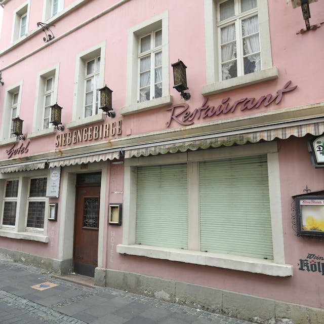 Ein ehemaliges Restaurant mit geschlossenen Rollläden an zwei Fenstern in der Fußgängerzone von Königswinter