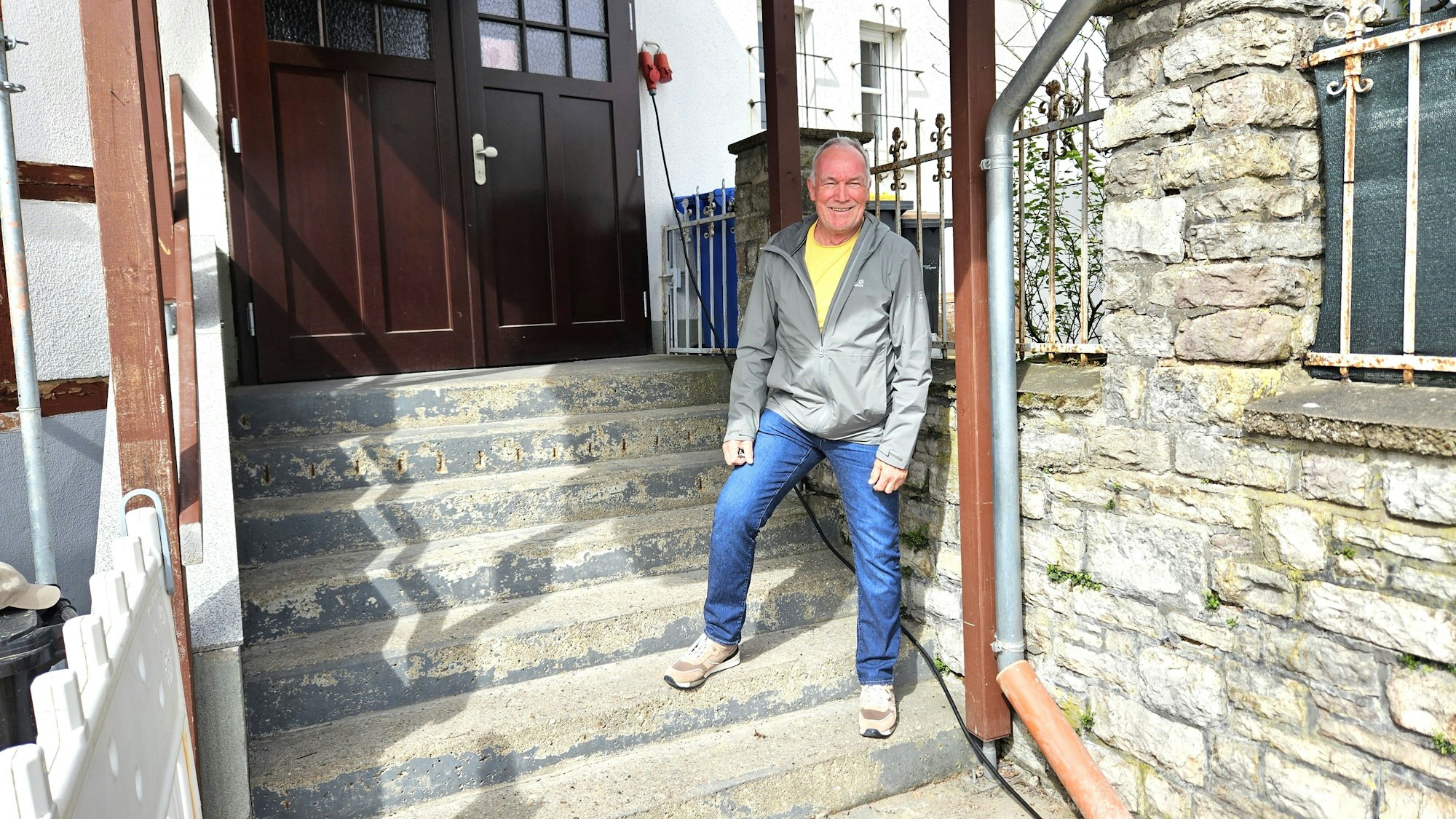 Peter Berbur steht auf einer Treppe, die zum Gasthaus führt.
