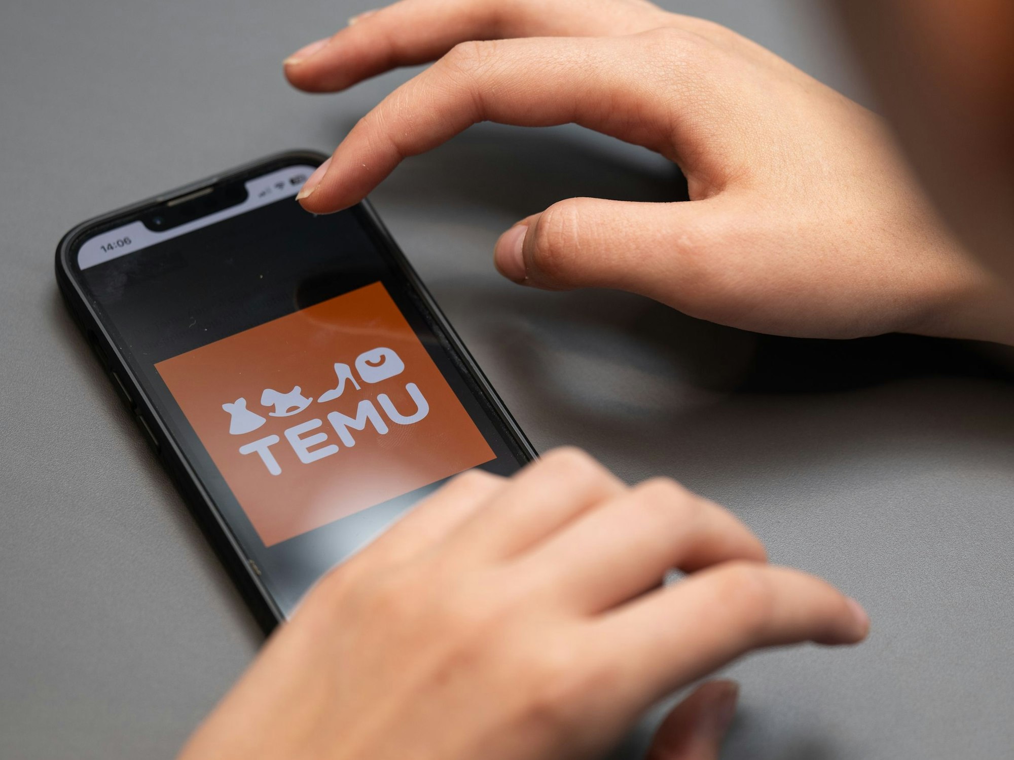 Eine Person hält ein Telefon mit der App Temu in den Händen, hier im August 2023 in Berlin.