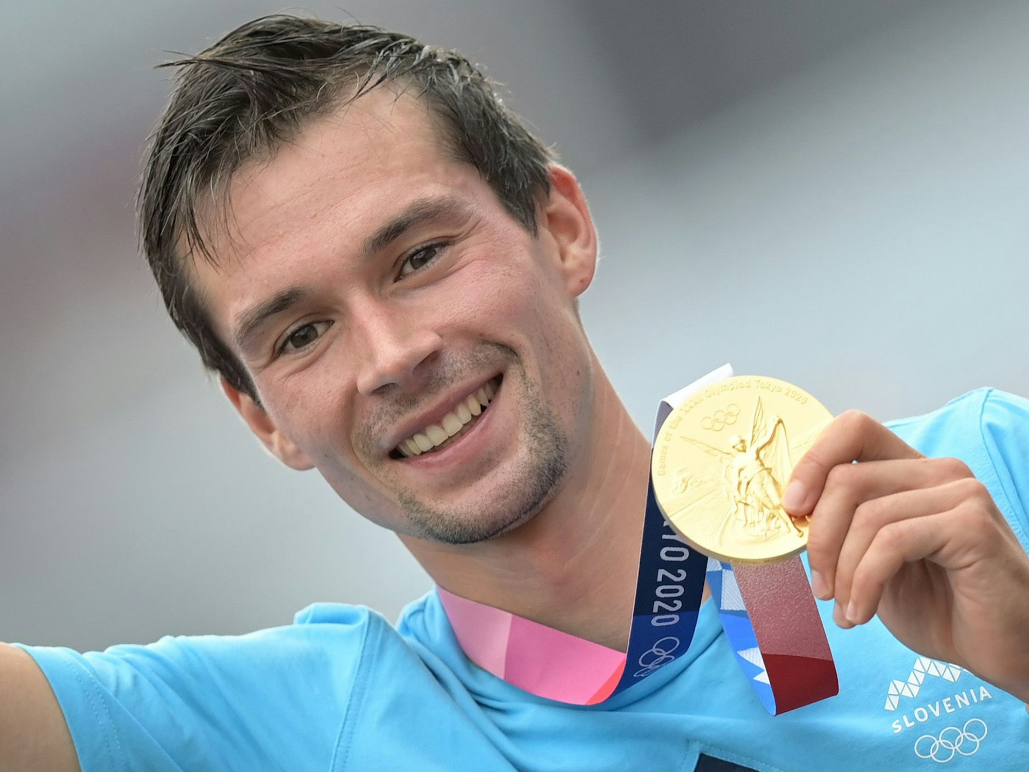 Primoz Roglic strahlt nach seinem Olympiasieg in Tokio mit seiner Goldmedaille um die Wette.