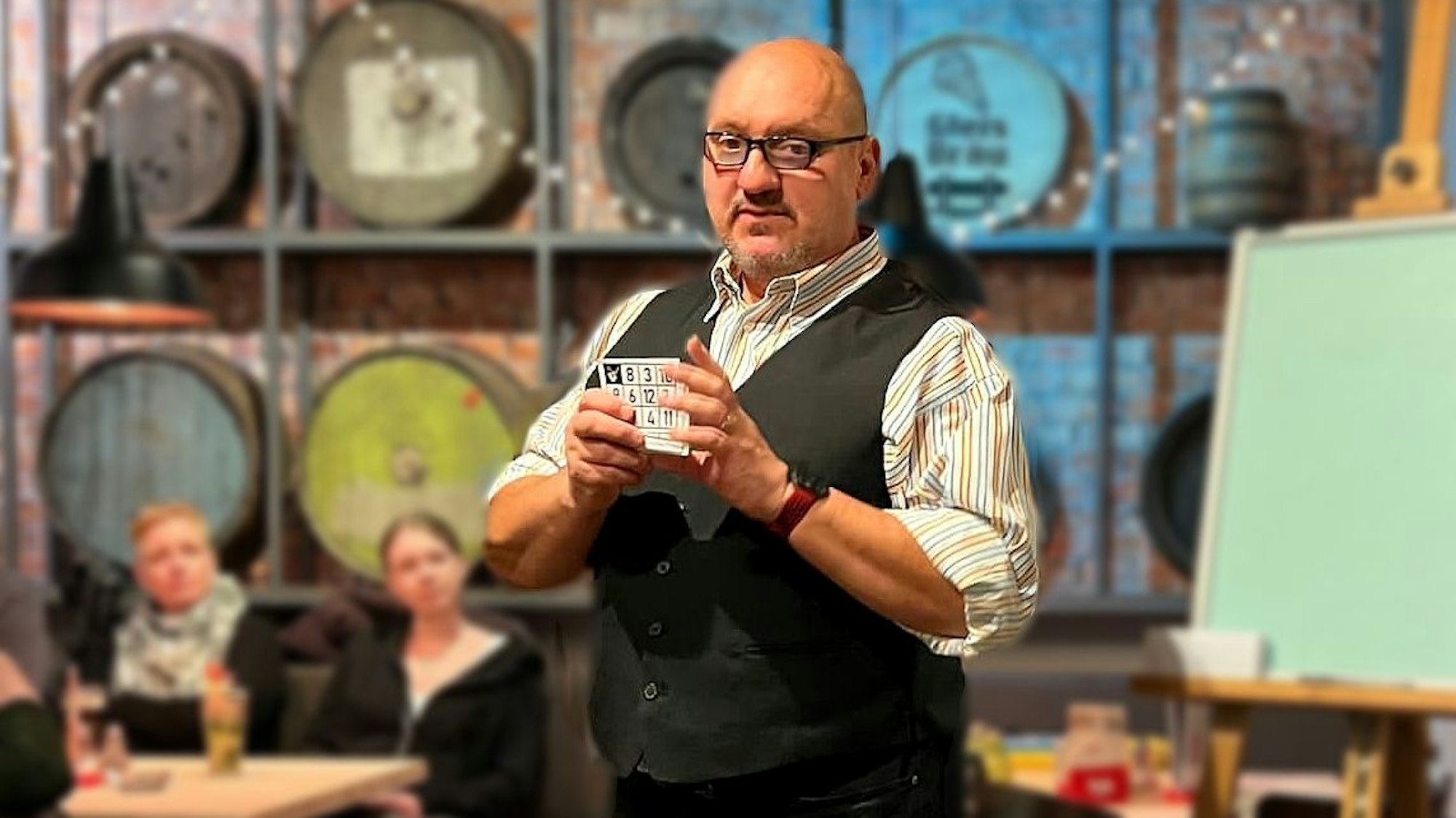 Ein Mann steht in einem Lokal mit Karten in der Hand.