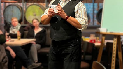 Ein Mann steht in einem Lokal mit Karten in der Hand.