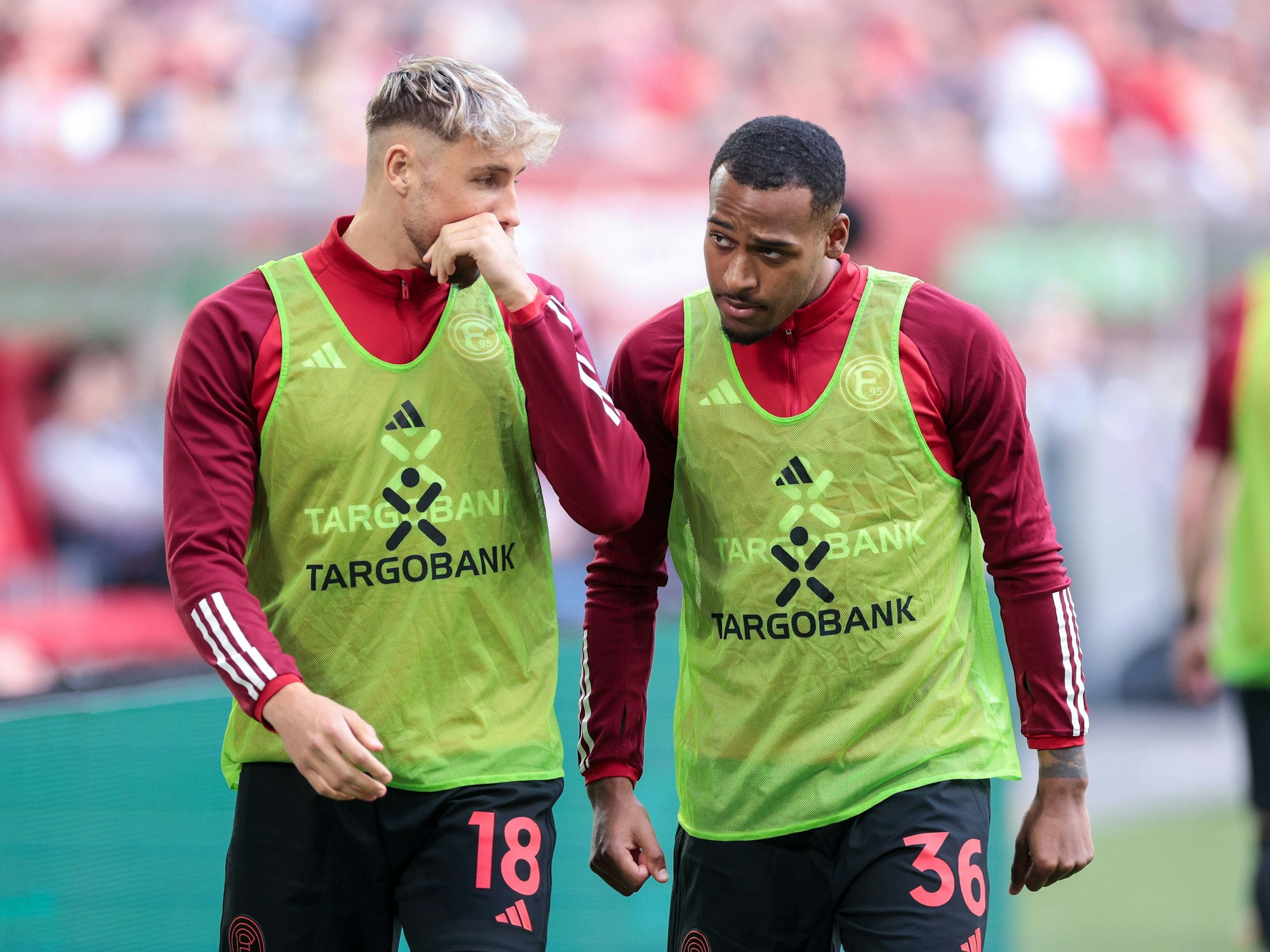 Die Düsseldorf-Profis Jona Niemiec und Marlon Mustapha unterhalten sich beim Aufwärmen am Seitenrand.
