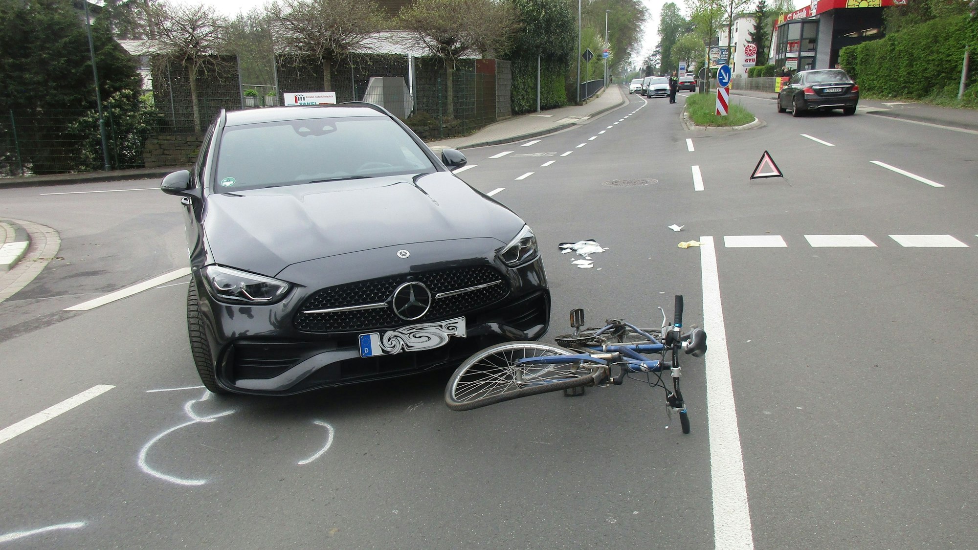 Ein Unfallauto steht neben einem schwer beschädigten Fahrrad an der Einmündung der Straße Venauen auf die Rösrather Hauptstraße.