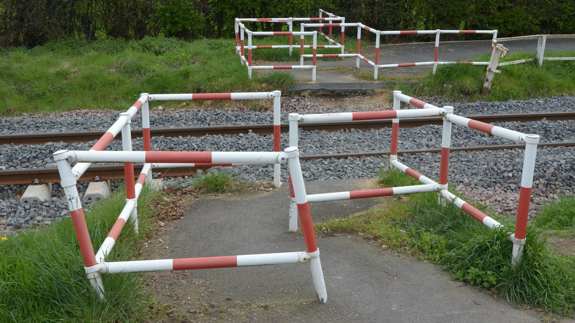 Das Bild zeigt rot-weiße Umlaufgitter auf beiden Seiten eines Bahnübergangs.