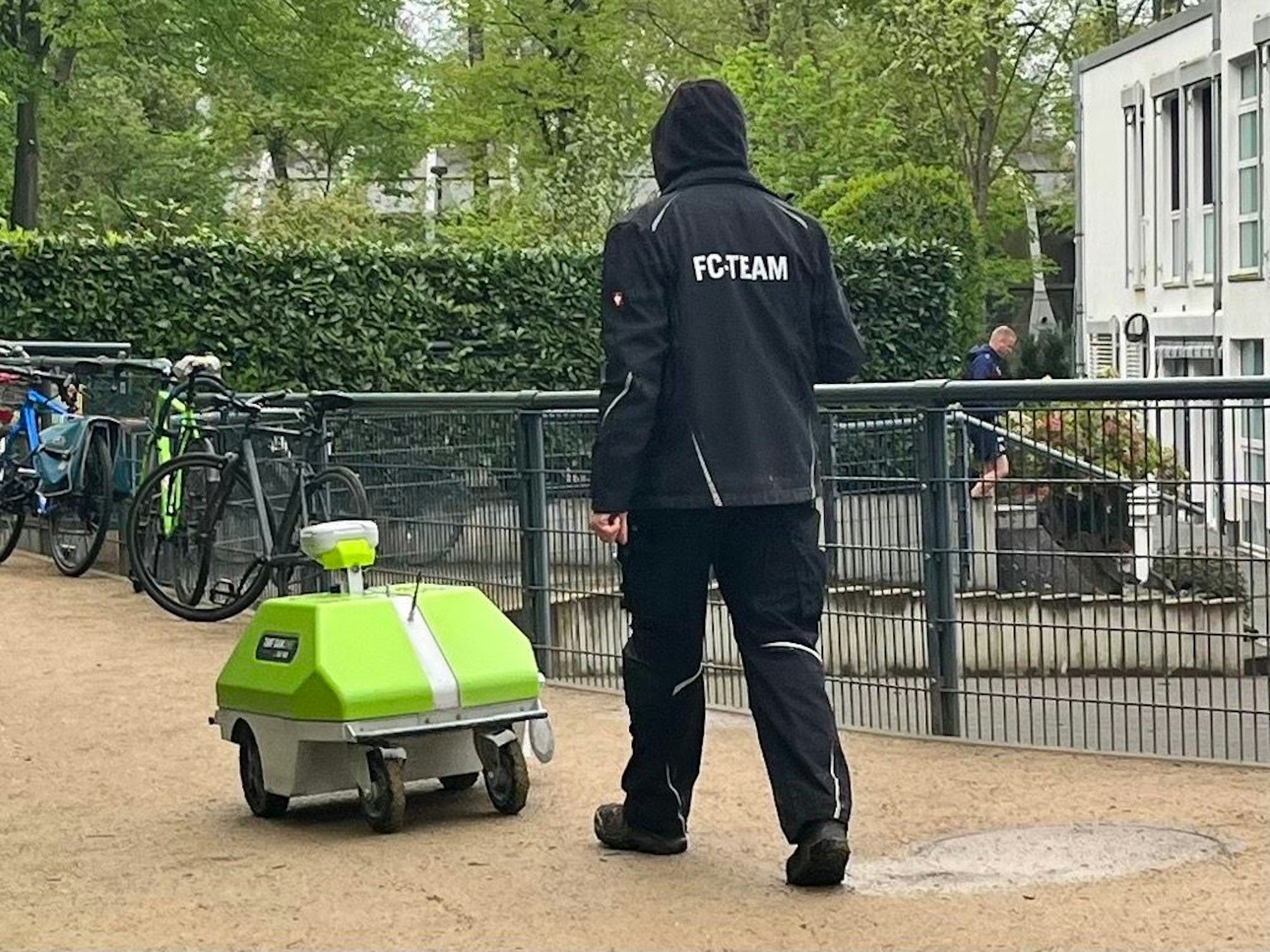 Ein FC-Mitarbeiter steuert einen Rasenroboter am Geißbockheim.