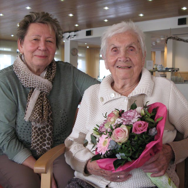 Die 102 Jahre alte Charlotte Seeger sitzt mit einem Blumenstrauß in den Händen neben ihrer 74-jährigen Tochter.