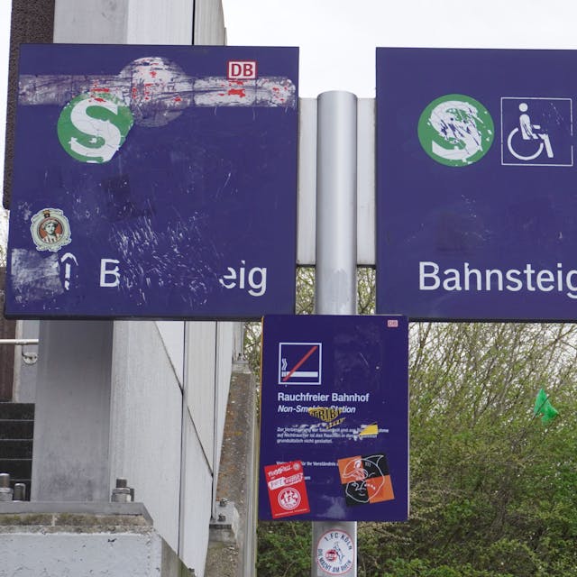 Das Bild zeigt Hinweisschilder der Deutschen Bahn, die verkratzt oder verklebt sind.