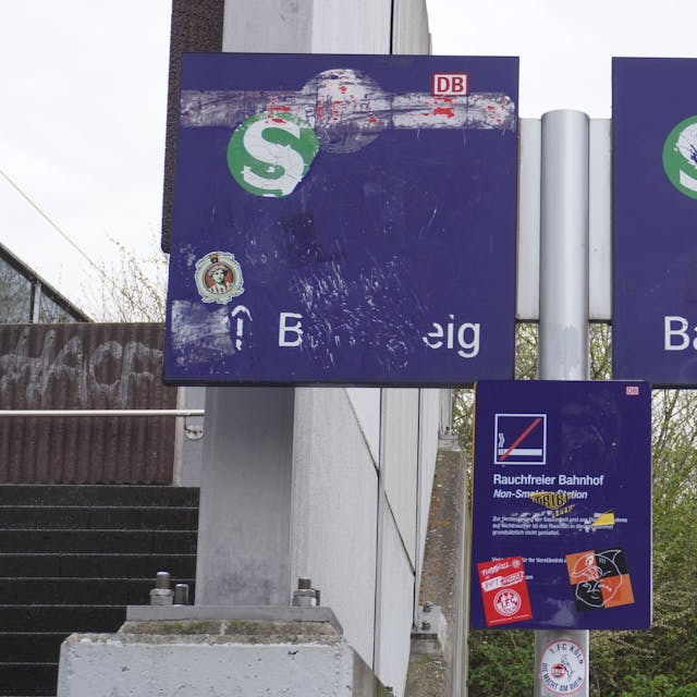 Das Bild zeigt Hinweisschilder der Deutschen Bahn, die verkratzt oder verklebt sind.