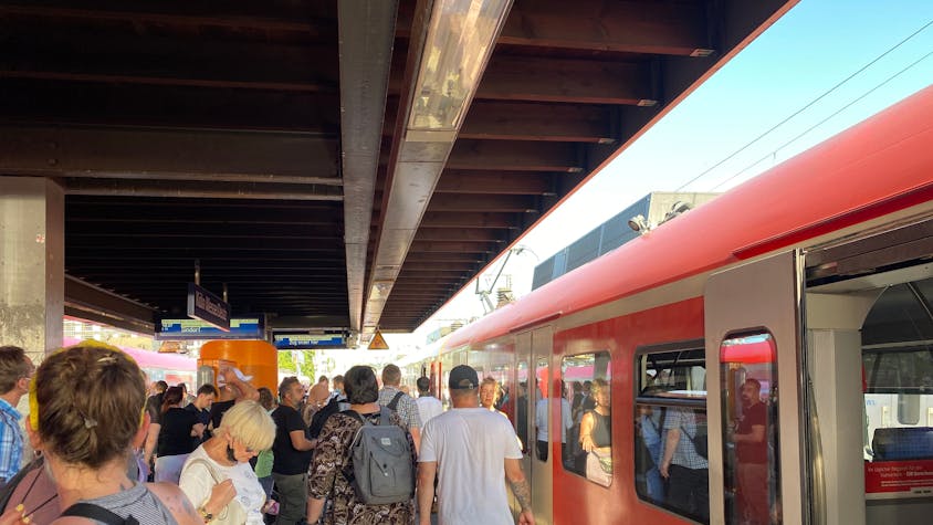Ein Zug der S-Bahnlinie 11 hält im Sommer an einem vollen Bahnsteig in Köln.