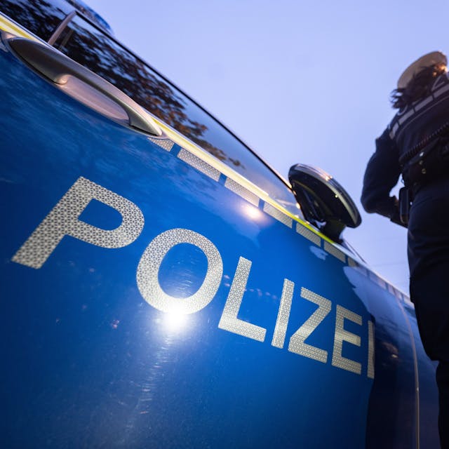 Eine Polizistin steht neben einem Polizeifahrzeug (Symbolbild).