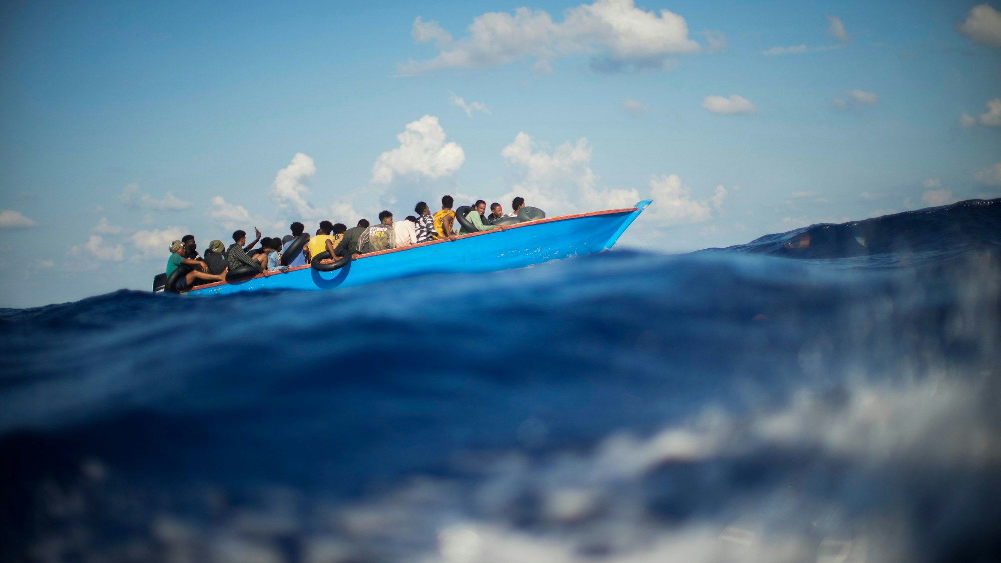 Migranten sitzen in einem Boot auf dem Meer.