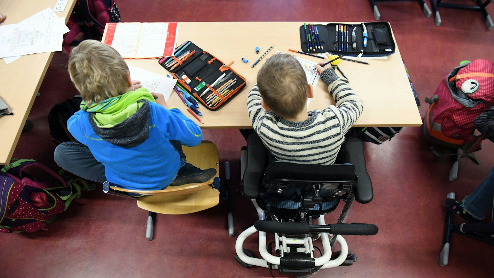 Ein Kind mit Behinderung sitzt in seinem Rollstuhl in einer Klasse.