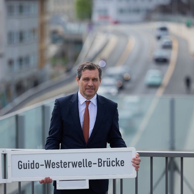 Michael Mronz, Ehemann von Guido Westerwelle und Witwer, hält das Schild mit dem neuen Namen der Brücke.