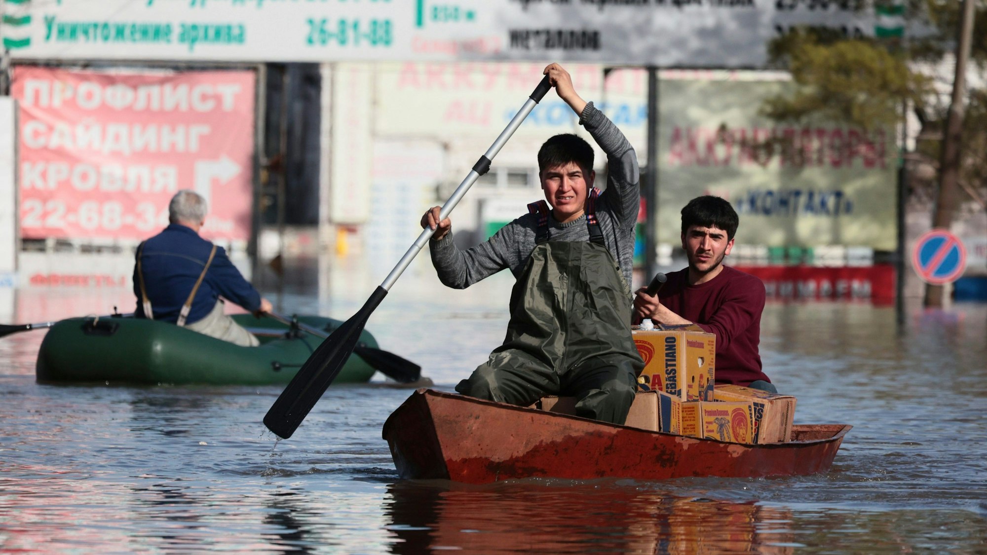 Zwei Männer rudern ein Boot durch das Hochwasser in Russland.