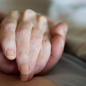 Ein Altenpfleger hält in einem Pflegeheim die Hand einer Frau.&nbsp;