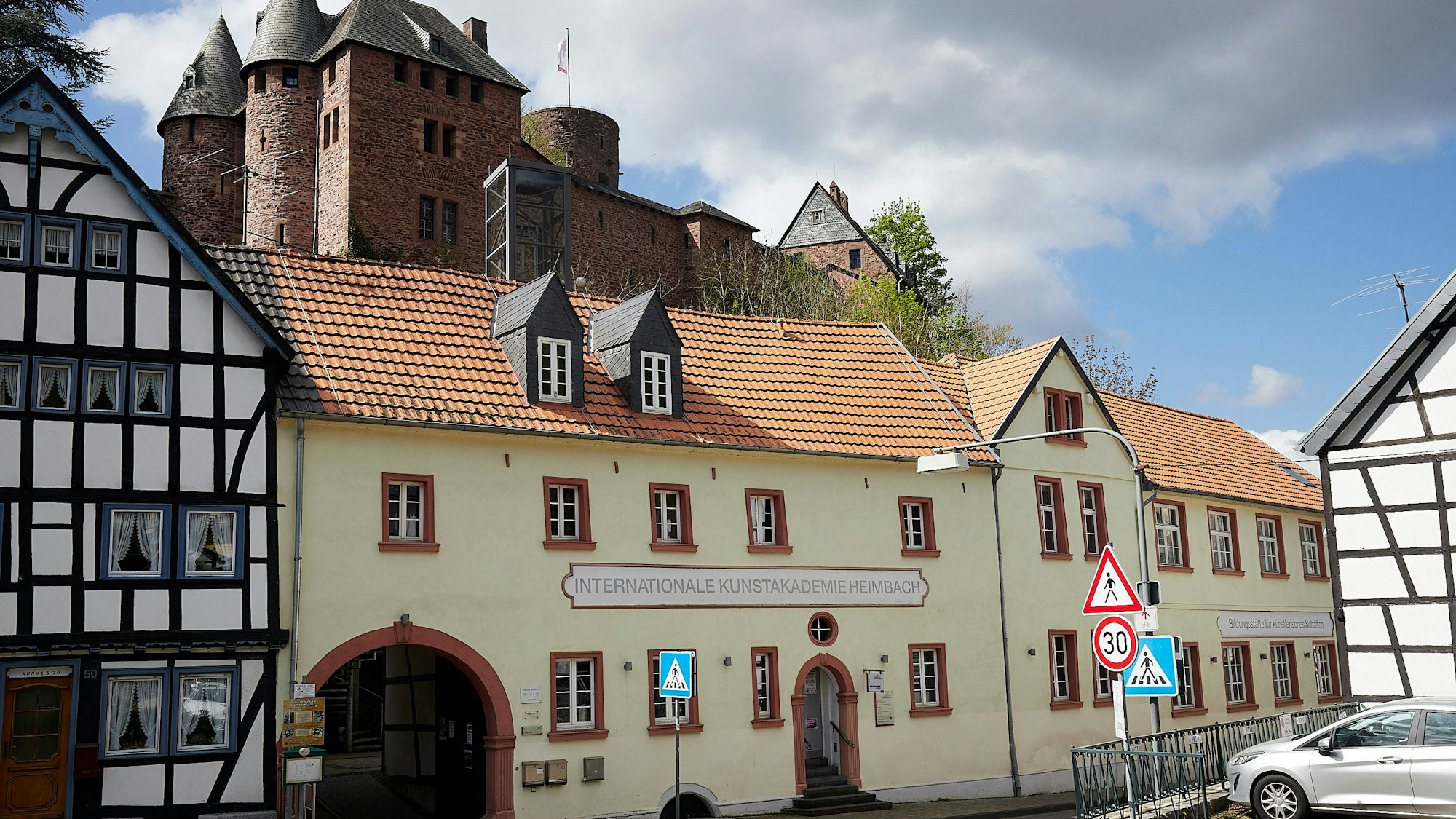 Das Bild zeigt die Internationale Kunstakademie in Heimbach. Im Hintergrund ist das Gemäuer der Burg Hengebach zu sehen.