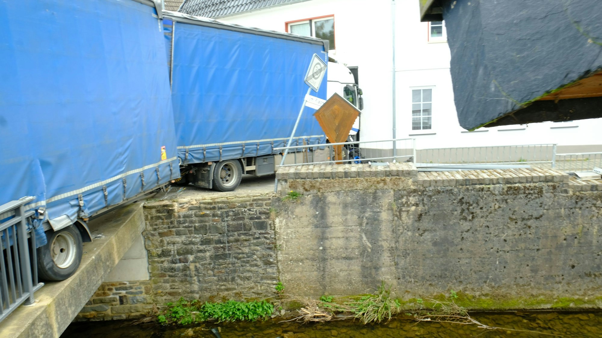 Der Anhänger des Lastwagens steht nah an der Brückenkante. Das Geländer und ein Teil der Mauer fehlen.
