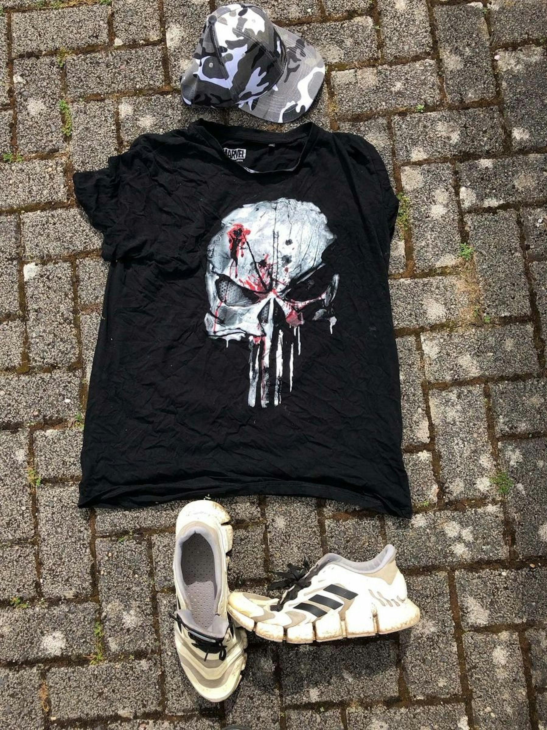 Auf dem Foto sind ein T-Shirt und Schuhe des unbekannten Mannes zu sehen.