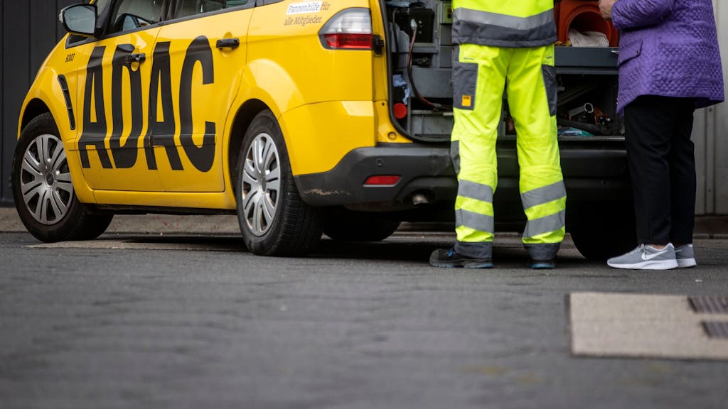 Ein Mitarbeiter des ADAC steht mit seinem gelben Fahrzeug an einer Straße in Duisburg und hilft einer Frau.&nbsp;