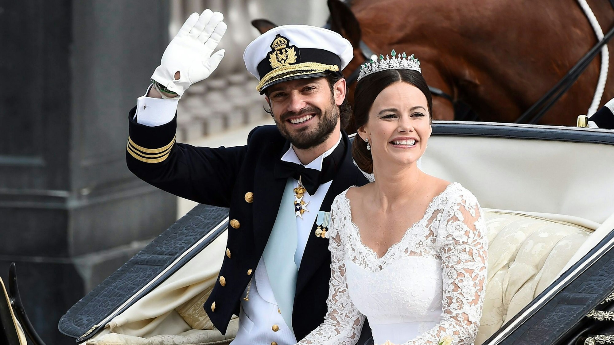 Prinz Carl Philip und Sofia Hellqvist winken der Menge von einer offenen Kutsche aus zu, nachdem sie am 13. Juni 2015 in der Kapelle des königlichen Schlosses in Stockholm, Schweden, geheiratet haben.