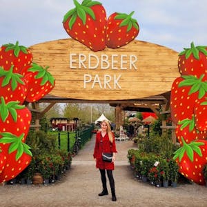 Auf dem Foto ist eine Besucherin vor einem Bogen aus überdimensionalen Erdbeeren zu sehen.
