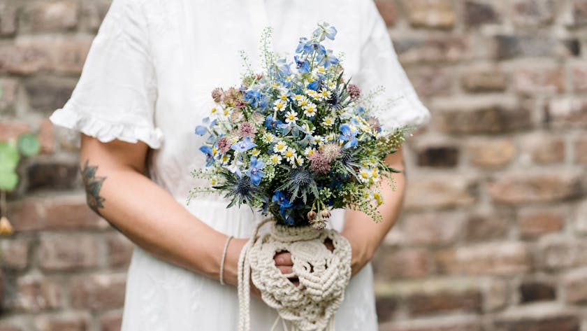 Eine Braut trägt ein Secondhand-Hochzeitskleid, der Brautstrauß besteht aus regionalen Wiesenblumen.