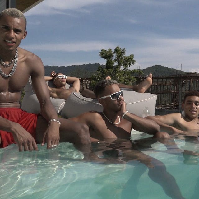 Vier junge Männer posieren und lümmeln am Pool.&nbsp;