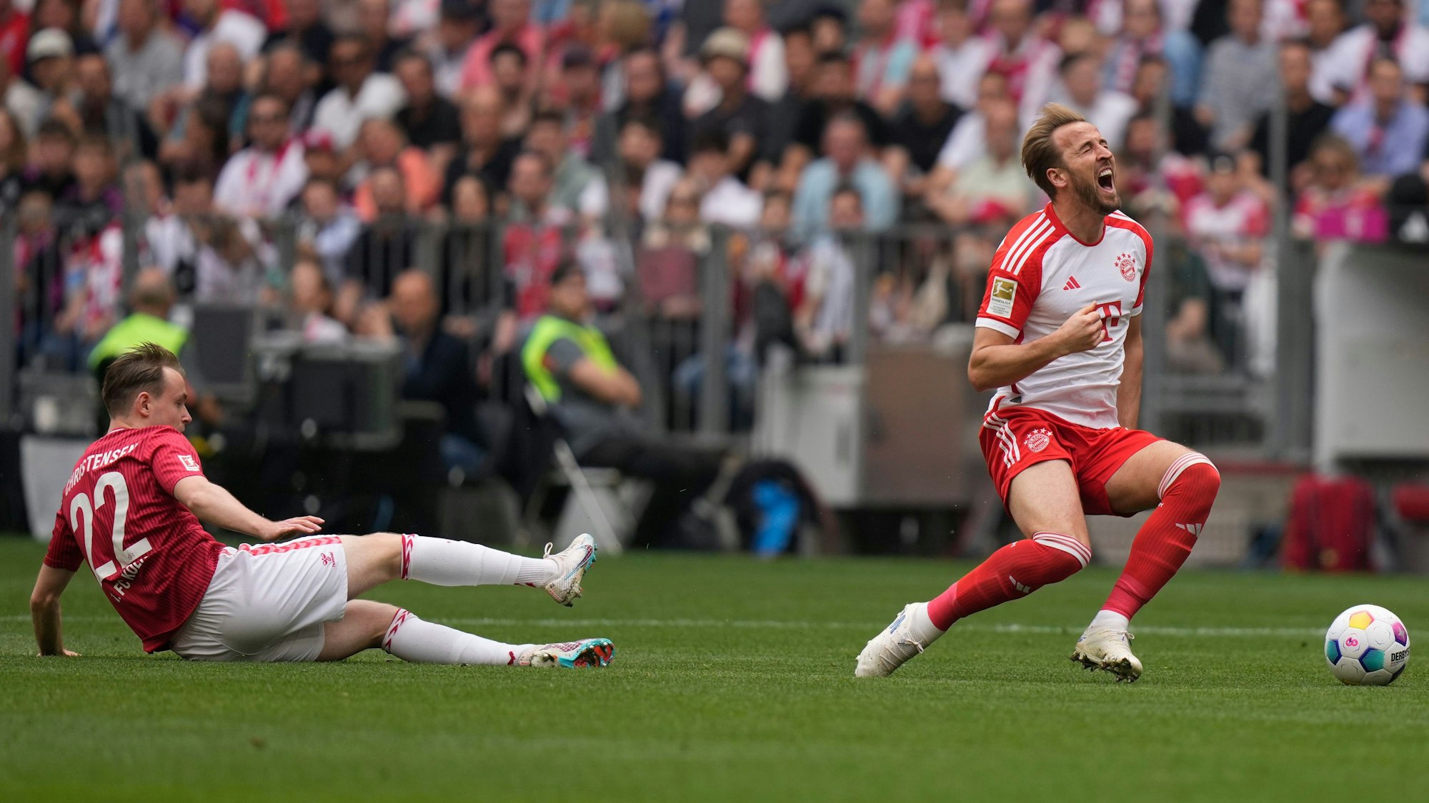 Bayern's Harry Kane grimaces as he is fouled by Cologne's Jacob Steen Christensen, left, during the German Bundesliga soccer match between Bayern Munich and Cologne at the Allianz Arena in Munich, Germany, Saturday, April 13, 2024. (AP Photo/Matthias Schrader)